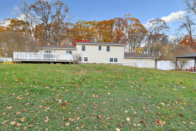 a view of house with a big yard and large trees