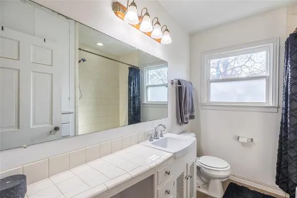 a bathroom with a granite countertop sink mirror vanity and toilet