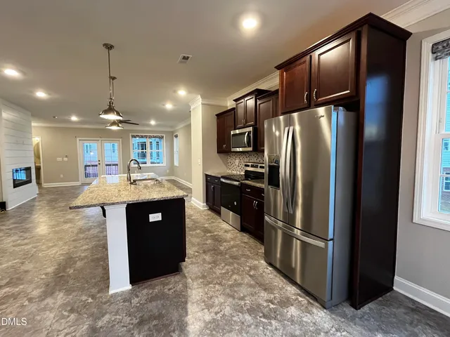 a kitchen with stainless steel appliances granite countertop a refrigerator a sink a stove and oven