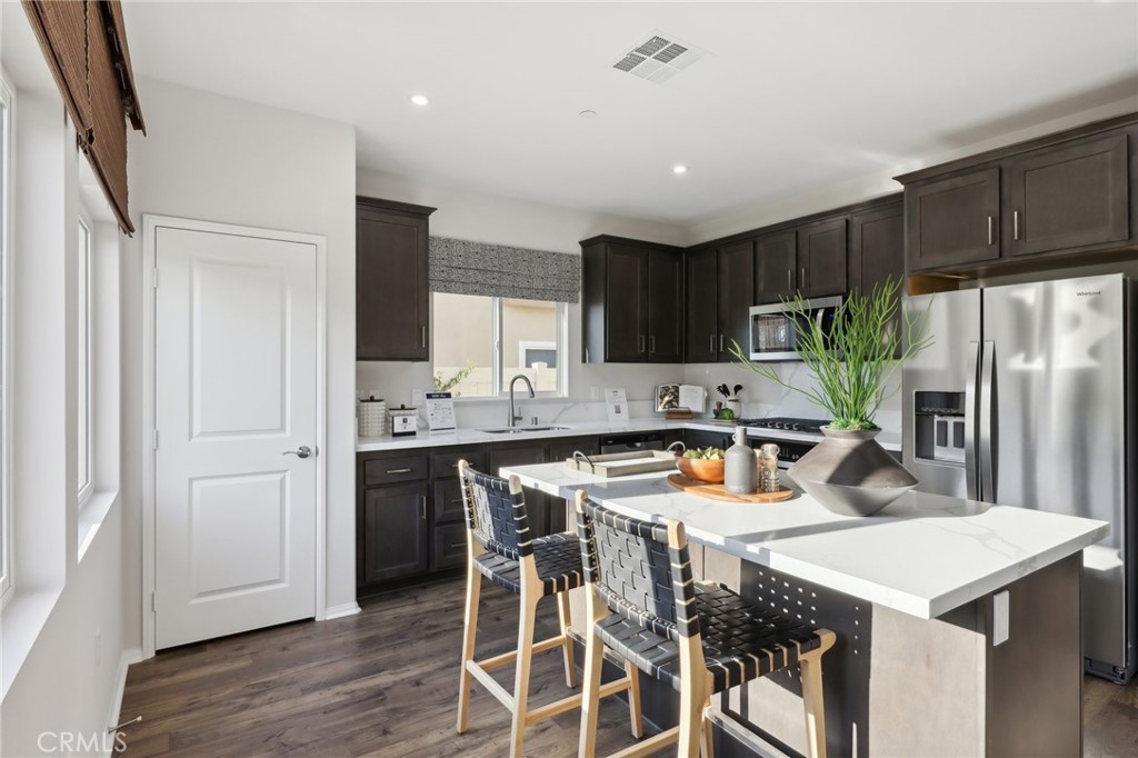 49459 Meadowlark Place Indio, CA 92201 - Photo 12 of 33 a kitchen with stainless steel appliances a table chairs refrigerator and sink