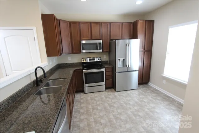 a kitchen with stainless steel appliances granite countertop a refrigerator a stove a sink and a counter space