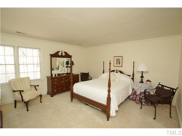7309 Mevan Court Raleigh, NC 27613 - Photo 16 of 22 a spacious bedroom with a bed a table and chair
