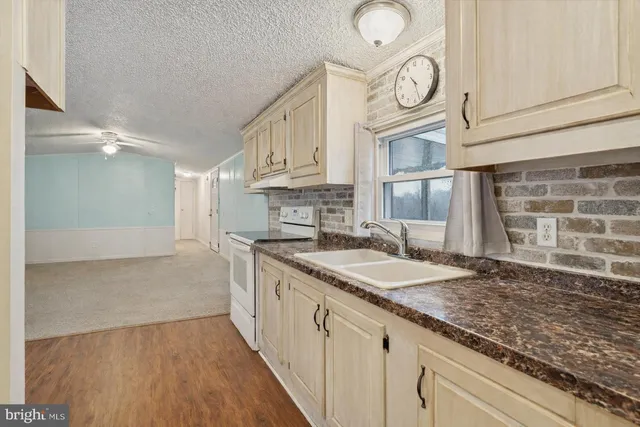 a kitchen with granite countertop a sink a stove and cabinets