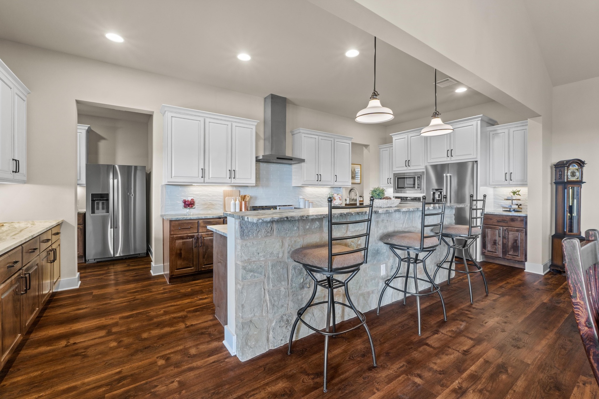 18817 Hidden Ridge Place Jonestown, TX 78645 - Photo 11 of 40 Kitchen with wall chimney exhaust hood, dark wood finished floors, backsplash, appliances with stainless steel finishes, and a breakfast bar area