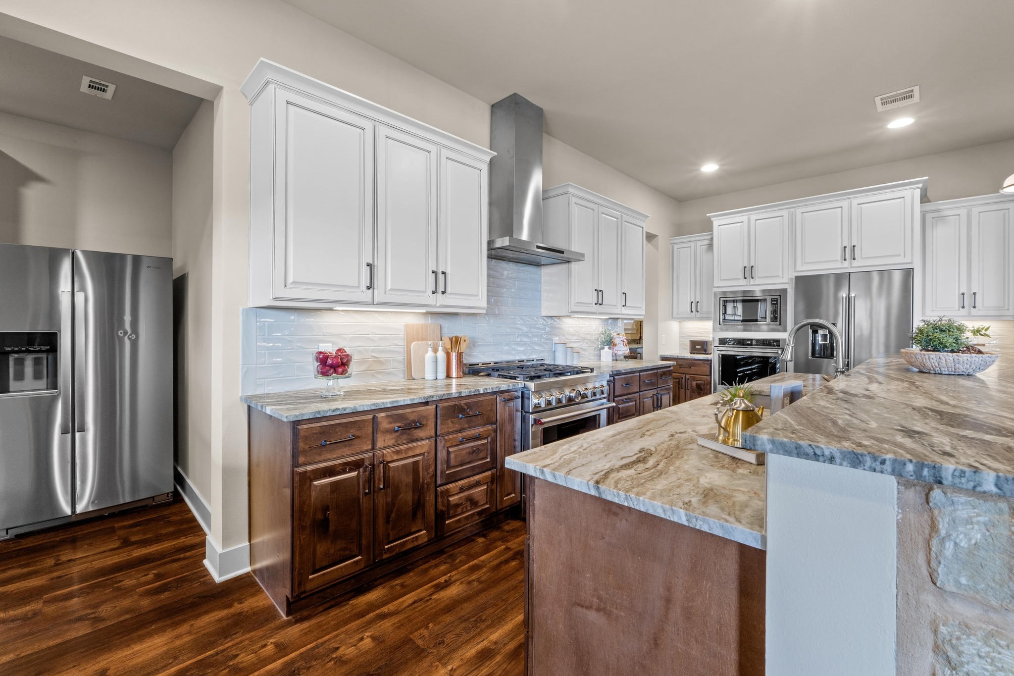 18817 Hidden Ridge Place Jonestown, TX 78645 - Photo 12 of 40 Kitchen featuring white cabinets, high end appliances, dark wood finished floors, wall chimney exhaust hood, and visible vents