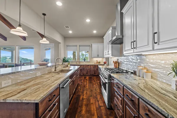 a large kitchen with stainless steel appliances granite countertop a stove and a view of living room