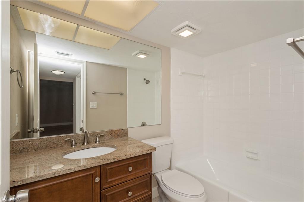 4963 Pepper Circle, Unit D202 Naples, FL 34113 - Photo 13 of 17 a bathroom with a granite countertop sink toilet a large mirror and shower