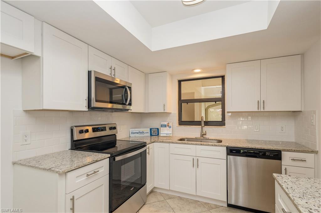 4963 Pepper Circle, Unit D202 Naples, FL 34113 - Photo 4 of 17 a kitchen with stainless steel appliances granite countertop white cabinets sink and window