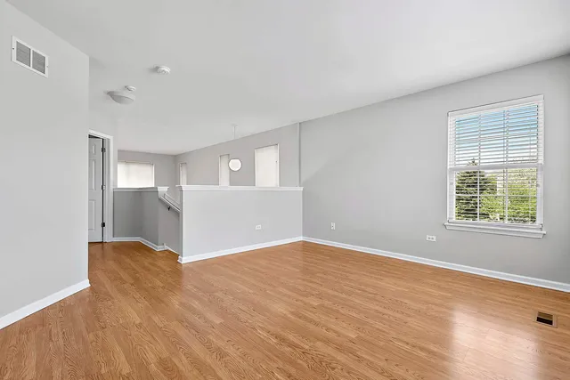 a view of empty room with wooden floor and fan