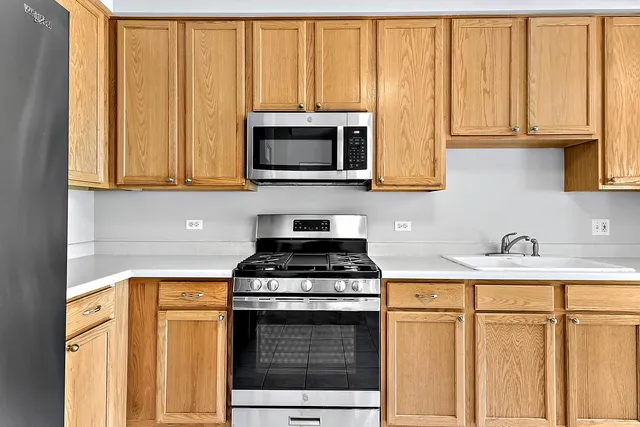 a kitchen with stainless steel appliances granite countertop a stove a sink and a microwave