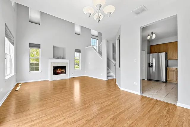 an empty room with wooden floor fireplace and windows