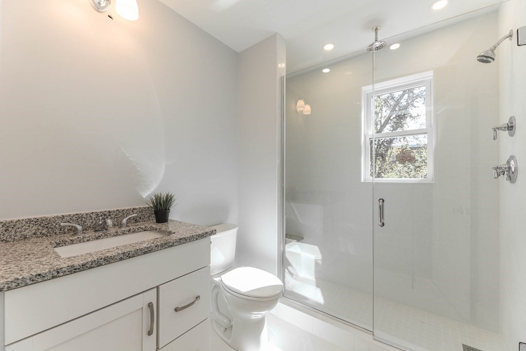 34 Colgate Road, Unit 2 Boston, MA 02131 - Photo 12 of 19 a bathroom with a granite countertop sink a toilet a mirror and shower