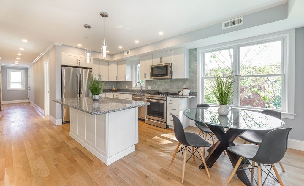 34 Colgate Road, Unit 2 Boston, MA 02131 - Photo 2 of 19 a kitchen with stainless steel appliances granite countertop a stove top oven a sink dishwasher a dining table and chairs with wooden floor
