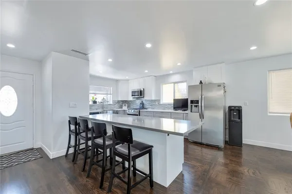 a kitchen with stainless steel appliances kitchen island granite countertop a table chairs sink and cabinets