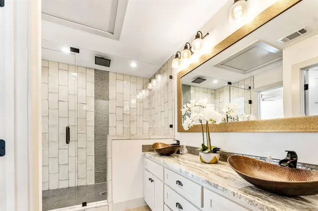 a bathroom with a granite countertop sink a mirror and shower