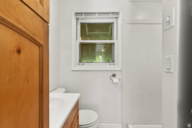 658 North 100 East Logan, UT 84321 - Photo 11 of 26 Bathroom featuring a window with blinds, a white vanity with an integrated sink, a toilet, and light wood-finish cabinetry
