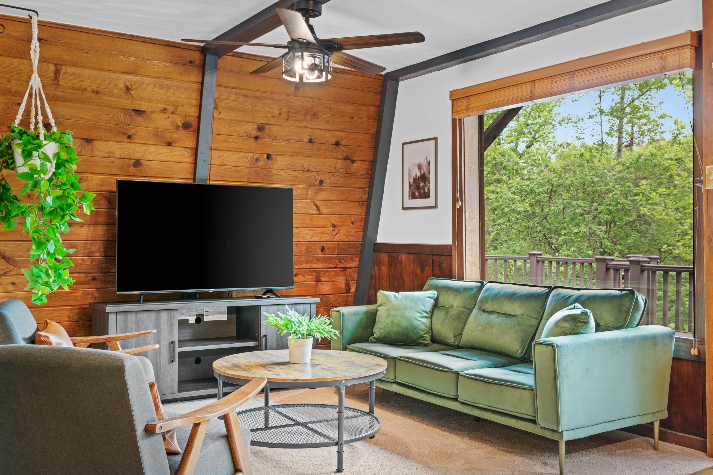a living room with furniture a flat screen tv and a floor to ceiling window