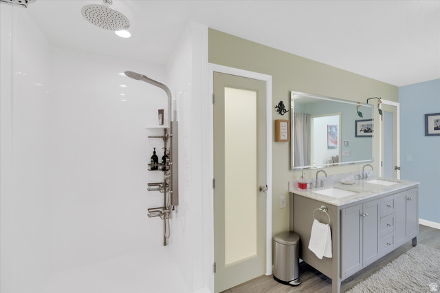 510 Spring Creek Road Providence, UT 84332 - Photo 28 of 97 Bathroom featuring a dual vanity with undermount sinks and a stone countertop, a large framed mirror, and a walk-in shower with a rain shower head and a multi-function shower panel
