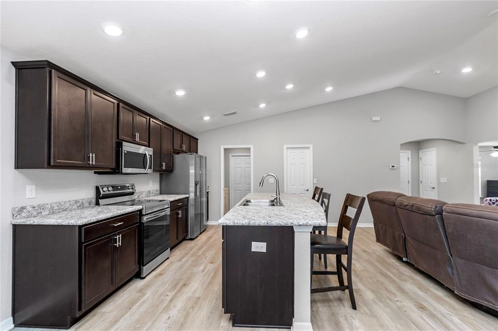 Undisclosed Address Ocala, FL 34480 - Photo 29 of 38 a kitchen with stainless steel appliances granite countertop wooden cabinets a refrigerator a sink a stove a dining table and chairs