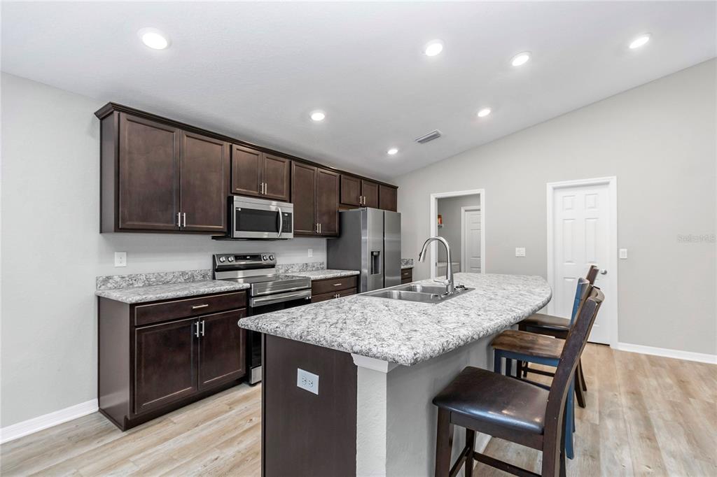 Undisclosed Address Ocala, FL 34480 - Photo 30 of 38 a kitchen with a stove a sink a microwave and wooden cabinets
