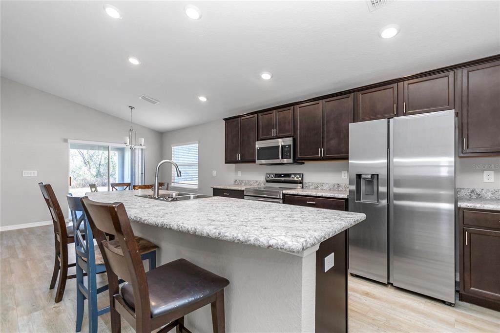 Undisclosed Address Ocala, FL 34480 - Photo 32 of 38 a kitchen with granite countertop a refrigerator and wooden cabinets