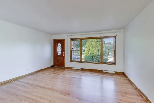 an empty room with wooden floor and a window