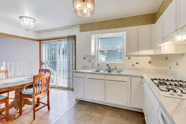a kitchen with stainless steel appliances a sink a stove a table and chairs