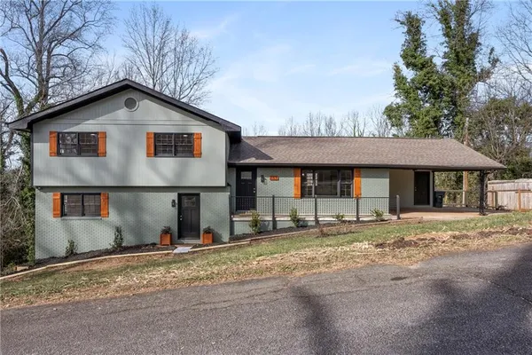 a view of a house with a yard and large tree