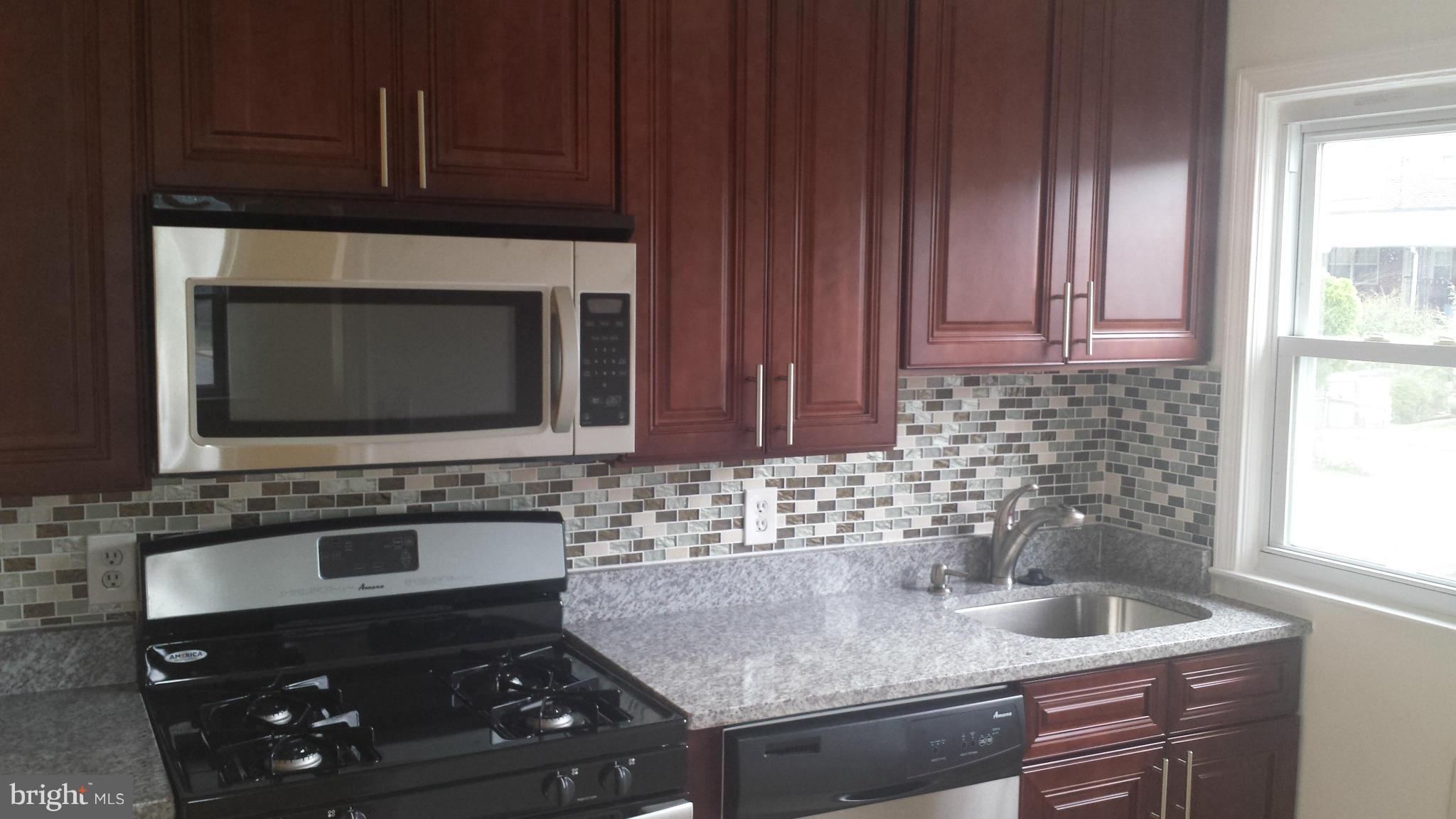 1560 Clairidge Road Baltimore, MD 21207 - Photo 7 of 16 a kitchen with granite countertop a sink a stove and cabinets