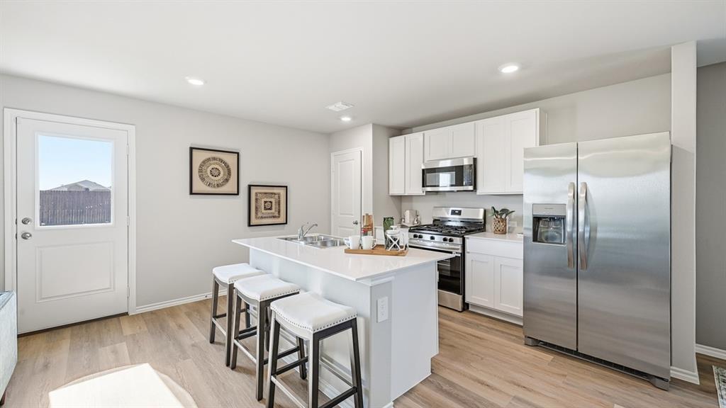 a kitchen with a refrigerator a microwave a stove and wooden floor