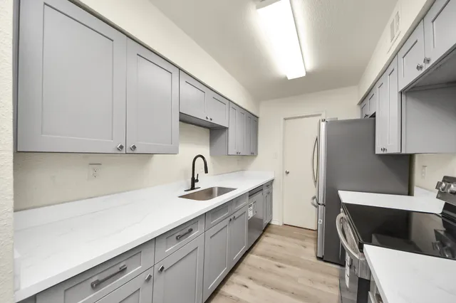 a kitchen with stainless steel appliances granite countertop a sink a stove and refrigerator