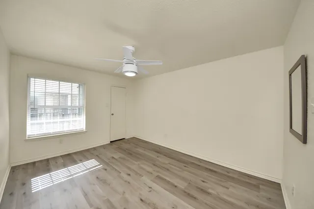 an empty room with wooden floor and ceiling fan