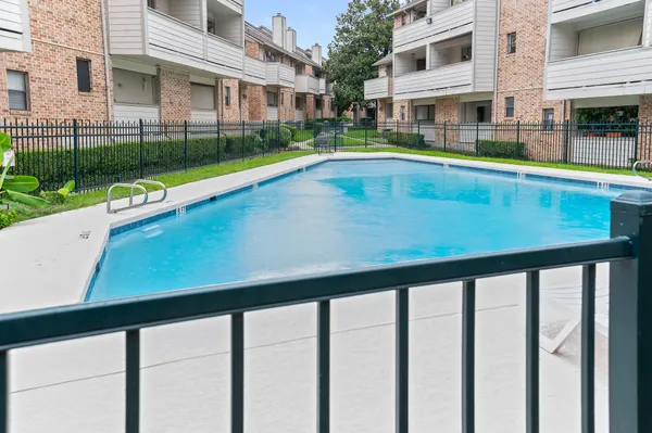 a view of an swimming pool with a yard from a balcony