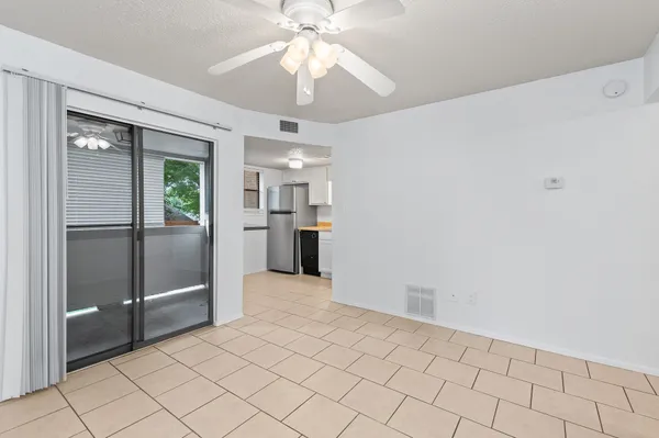 an empty room with chandelier fan and windows