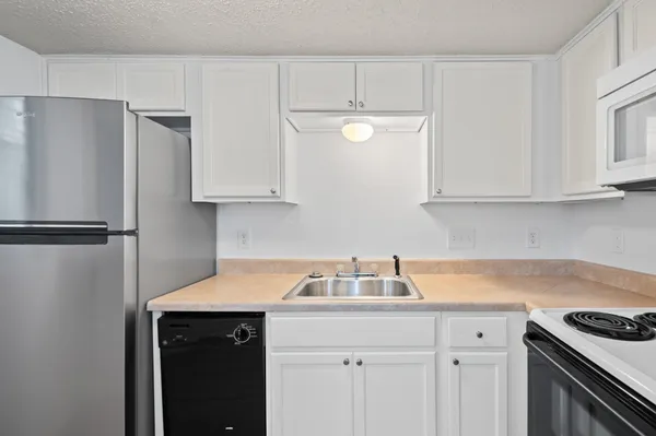 a kitchen with stainless steel appliances a refrigerator a sink and white cabinets