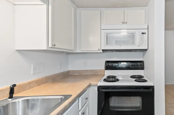 a kitchen with granite countertop white cabinets and a stove top oven