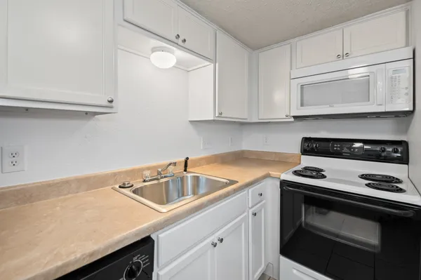 a kitchen with white cabinets sink and stove