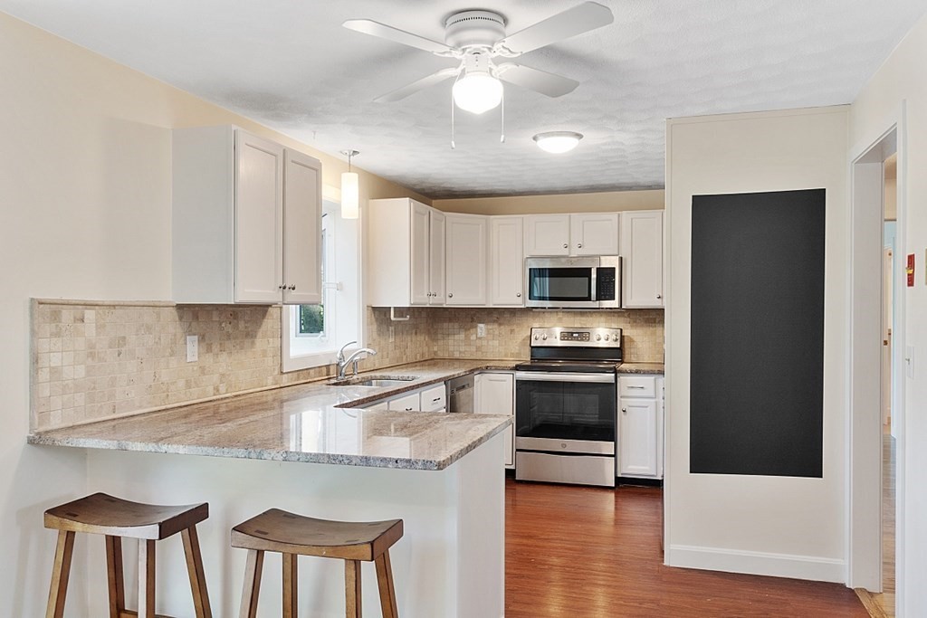 71 Mill Road Littleton, MA 01460 - Photo 5 of 30 a kitchen with stainless steel appliances granite countertop a stove a sink and a refrigerator with white cabinets