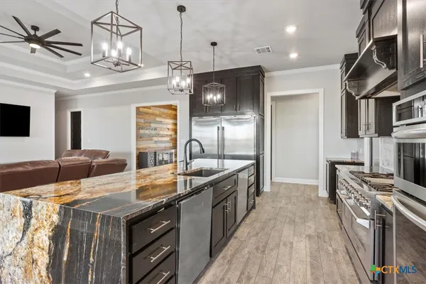 a kitchen with stainless steel appliances granite countertop a sink a stove and a refrigerator