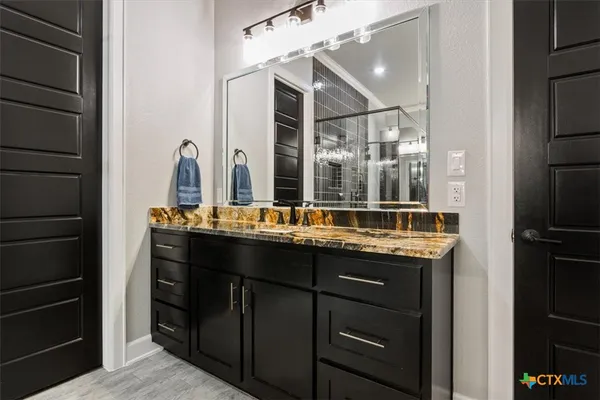 a bathroom with a granite countertop sink a mirror and a shower