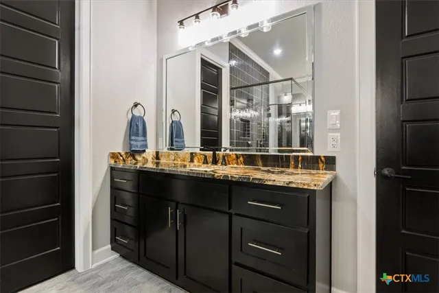 a bathroom with a granite countertop sink a mirror and a shower