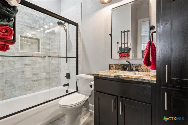 a bathroom with a granite countertop sink toilet and shower