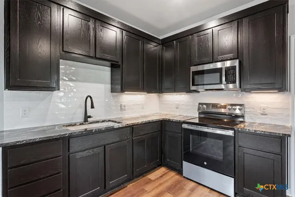 a kitchen with granite countertop cabinets stainless steel appliances and a sink