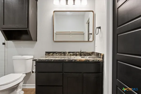 a bathroom with a granite countertop toilet sink and mirror