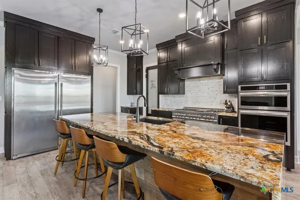 a kitchen with stainless steel appliances kitchen island granite countertop a table chairs stove and refrigerator