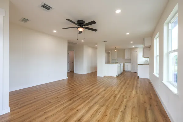 a view of an empty room with a window and wooden floor