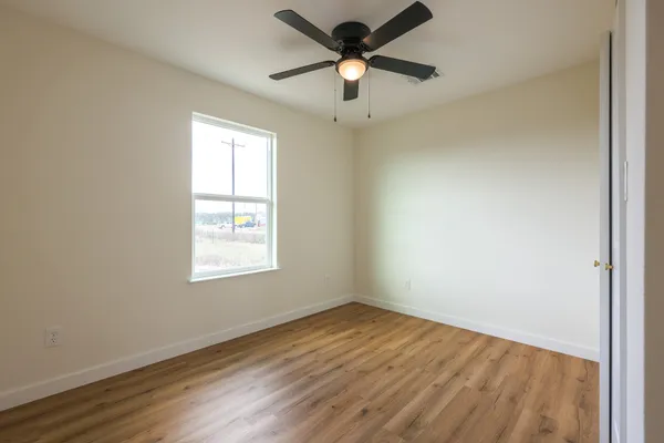 an empty room with a window and a fan