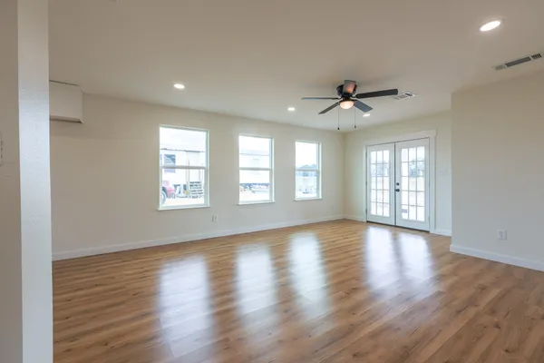 a view of an empty room with wooden floor and a window
