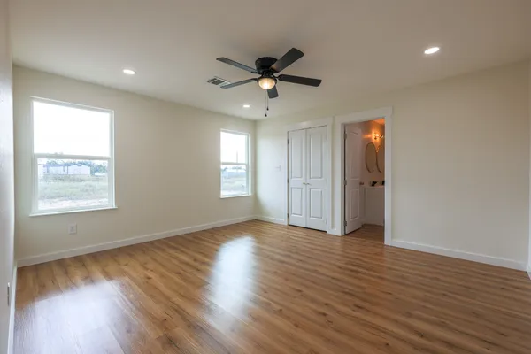 a view of empty room with wooden floor and fan