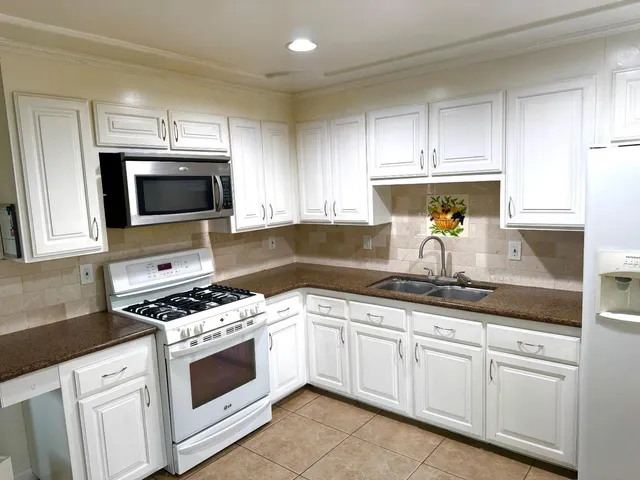 a kitchen with granite countertop white cabinets and white appliances